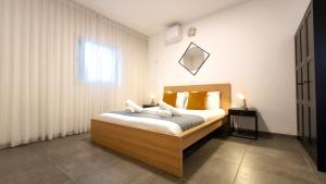 a bedroom with a bed with white sheets and a window at סי כנרת- דירות עם בריכה פרטית מבית בלו מגדל in Migdal