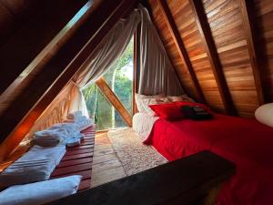 a bedroom with a red bed in a wooden house at Cabana Aracuã in Três Coroas