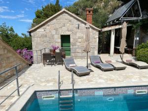 a pool with chairs and a table and a house at Villa Zeleni raj in Omiš