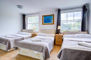 a bedroom with three beds and two windows at Saint Peter Hotel in London