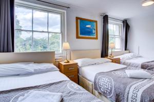 a bedroom with three beds and a window at Saint Peter Hotel in London