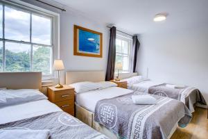 three beds in a room with three windows at Saint Peter Hotel in London