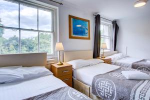 a bedroom with three beds and two windows at Saint Peter Hotel in London