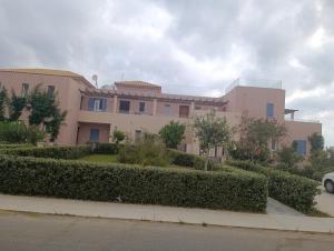 a large pink house with bushes in front of it at Apartment Odysea in Platanias