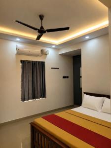 a bedroom with a bed with a ceiling fan at Hotel Grand Illam in Ernakulam