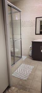 a bathroom with a glass shower and a rug at Spice N Honey in Port-of-Spain