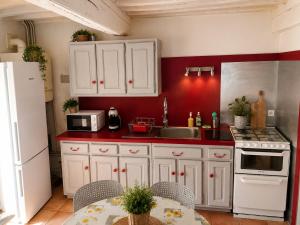 a kitchen with white cabinets and a red wall at La Longère de la Promenade in Château-Chinon +20 photos