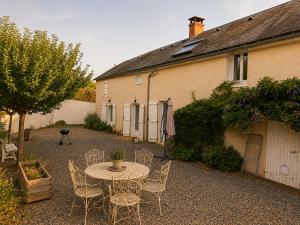 a patio with a table and chairs and a building at La Longère de la Promenade in Château-Chinon
