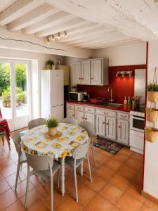 a kitchen with a table with chairs and a refrigerator at La Longère de la Promenade in Château-Chinon