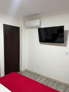 a room with a red rug and a flat screen tv at Apartamento Central in Montes Claros