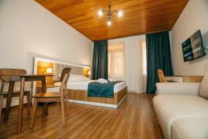 a bedroom with a bed and a table and a couch at Villa Mirakula Kvariati in Kvariati