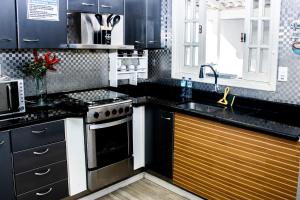 a kitchen with black cabinets and a stove top oven at pousada campolim prox ao hospital Bos in Sorocaba