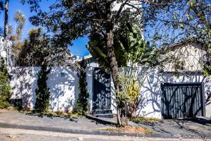 a white house with a gate and a tree at pousada campolim prox ao hospital Bos in Sorocaba