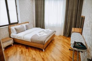 a bedroom with a bed with white sheets and wooden floors at Quba Garden Resort in Quba