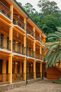 an orange building with balconies and a palm tree at Villa Mirakula Kvariati in Kvariati