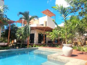 a pool in front of a house with palm trees at Design Luxury Villa in Holbox Island