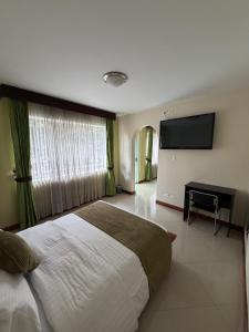 a bedroom with a large bed and a flat screen tv at Apartahotel Vincent Suites in Pasto