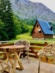 a wooden picnic table and two chairs and a cabin at Djedina Gora Cabins in Poda