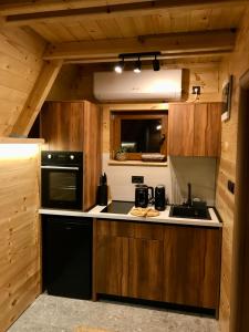 a kitchen with wooden cabinets and a sink and a stove at Djedina Gora Cabins in Poda +26 photos
