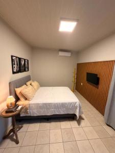 a bedroom with a bed and a table and a tv at Apto centro 03 in Tubarão