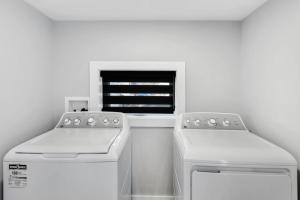a white kitchen with two machines and a window at Modern 1 Bdrm with Laundry, BBQ, Deck in Welland