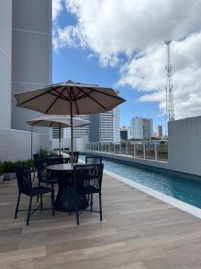 a table and chairs with an umbrella on a rooftop at Apartamento Bitú in Fortaleza