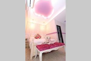 a white bedroom with a teddy bear sitting on a bench at Qing Noise Villas in Hualien City