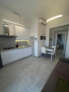 a kitchen with white cabinets and a table with chairs at Loft Pietrasanta in Pietrasanta
