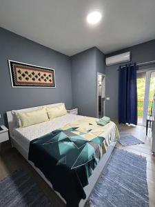a bedroom with a large bed with blue walls at Bujtina e Qilimave in Zogaji