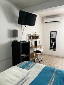 a bedroom with a bed and a desk with a television at Casa Múkara del Puerto in Veracruz