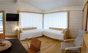 a bedroom with two beds and a tv and a table at Bungalow Camping Los Manzanos in Santa Cruz de Oleiros +66 photos