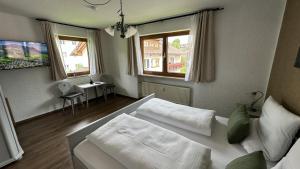 a bedroom with a white bed and two windows at Gästehaus Zoller - Rettenberg im Allgäu in Rettenberg