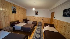 three beds in a room with wooden walls at Gudani Temi in Gudani