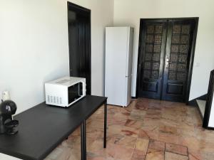 a room with a table with a microwave and a refrigerator at Conceição Guesthouse in Tavira