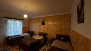 a room with two beds in a room with wooden walls at Gudani Temi in Gudani