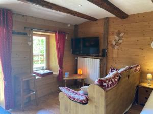 a living room in a log cabin with a couch and a television at Le Moulin de Bisanne in Villard-sur-Doron