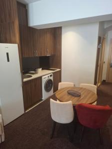 a kitchen with a table and chairs and a kitchen with a refrigerator at Lunas Apartmani in Kopaonik