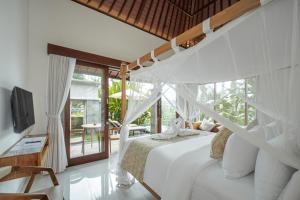 a bedroom with a white bed and a balcony at Puri Diamond Villas in Tampaksiring