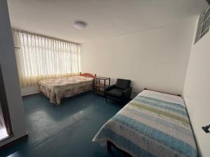 a bedroom with two beds and a chair and a window at Oasis in Tacna