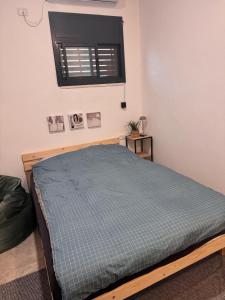 a bedroom with a bed with a blue blanket at קסם צפתי- סטודיו in Safed
