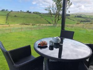 a table and chairs with a plate of food on it at Luxury Glamping Cabin sleeping 4 People with Private Hot Tub and BBQ with views across the North Coast Ballycastle Pod 2 in Ballycastle +4 photos