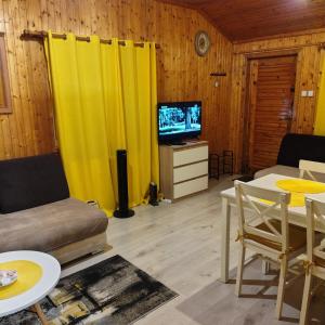 a living room with yellow curtains and a tv at Domek u Prezesa in Kłótno