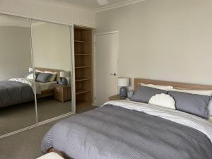a bedroom with a large bed and a mirror at Coastal Holiday House in Hawks Nest