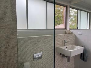 a bathroom with a sink and a glass shower at Coastal Holiday House in Hawks Nest