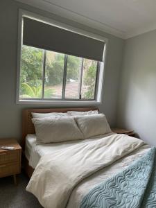a bedroom with a bed and a large window at Coastal Holiday House in Hawks Nest