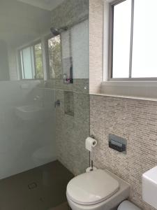 a bathroom with a toilet and a shower and a sink at Coastal Holiday House in Hawks Nest