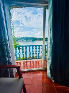 a room with a view of the water from a balcony at Maple Guest House in Flores