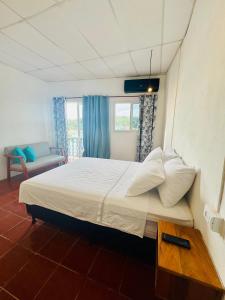 a bedroom with a large bed with white sheets and pillows at Maple Guest House in Flores