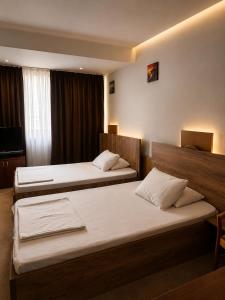 a hotel room with two beds and a television at The Square Central Prishtina in Prishtinë