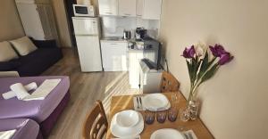 a living room with a table with purple flowers on it at Sun Sea 2 in Shkorpilovtsi